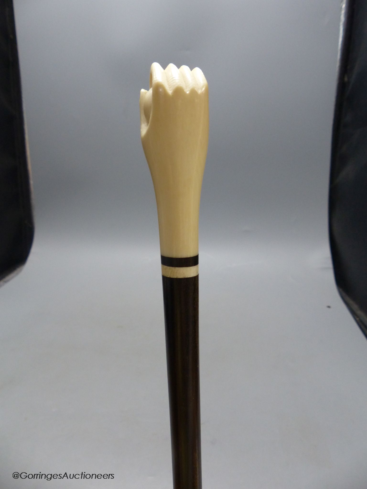 A rosewood and ivory handled walking stick in the form of a hand holding a ball